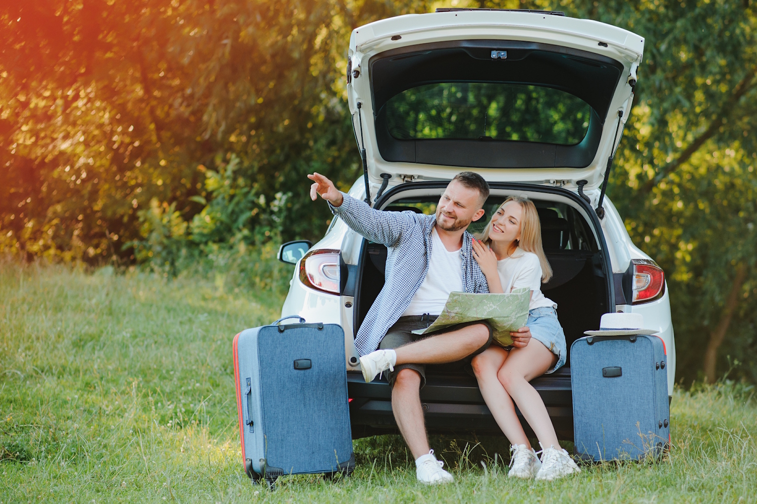 Couple of traveler sitting on hatchback of car near the road during holiday. TravellersInCar